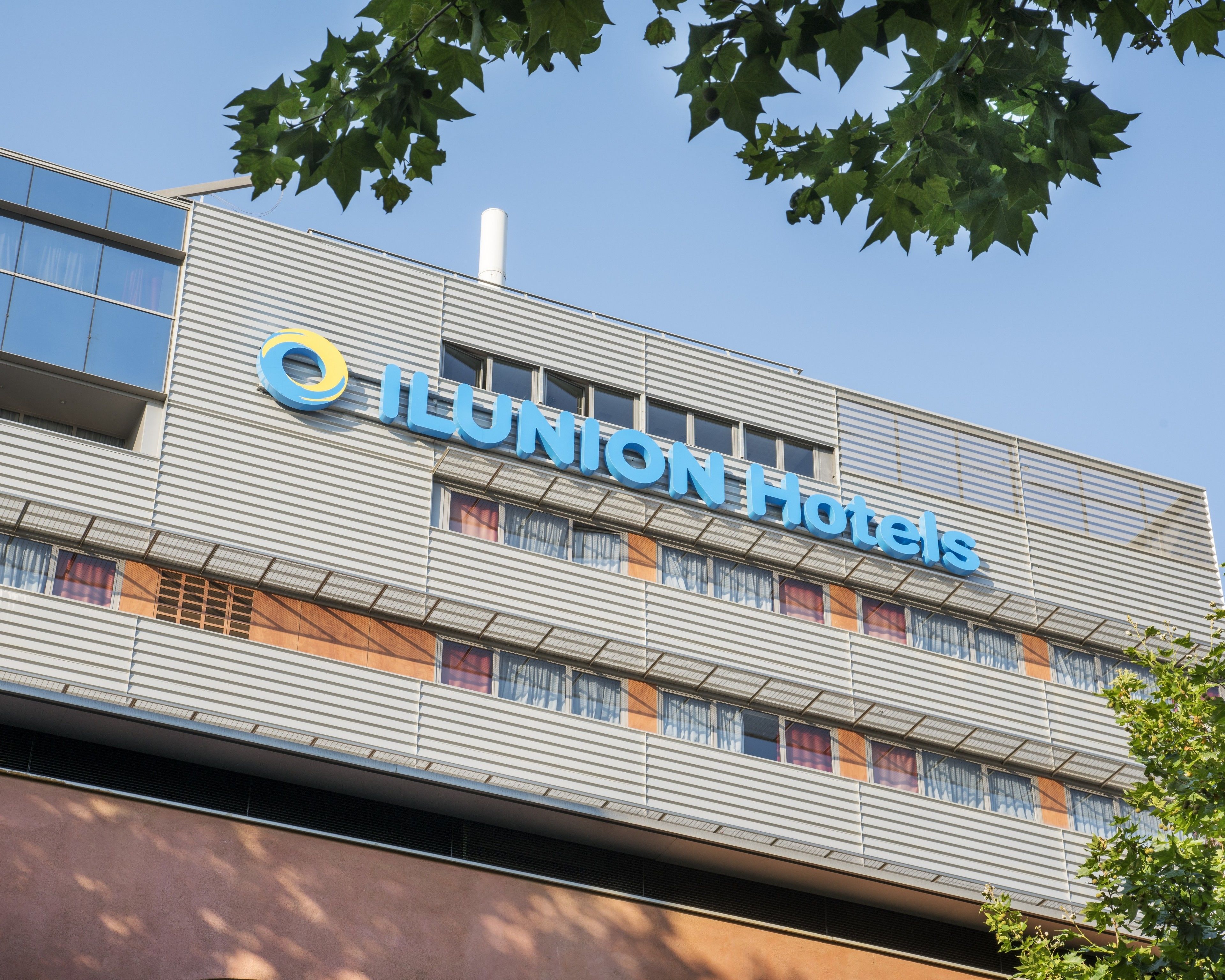A modern hotel building with the name "ILUNION Hotels" prominently displayed on the facade.
