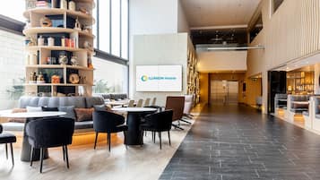 Un moderno vestíbulo de hotel con una zona de estar, un mostrador de recepción y un gran cartel de ILUNION Hotels.