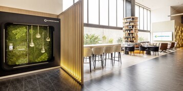 A modern hotel lobby with a reception desk, seating area, and a large bookshelf.