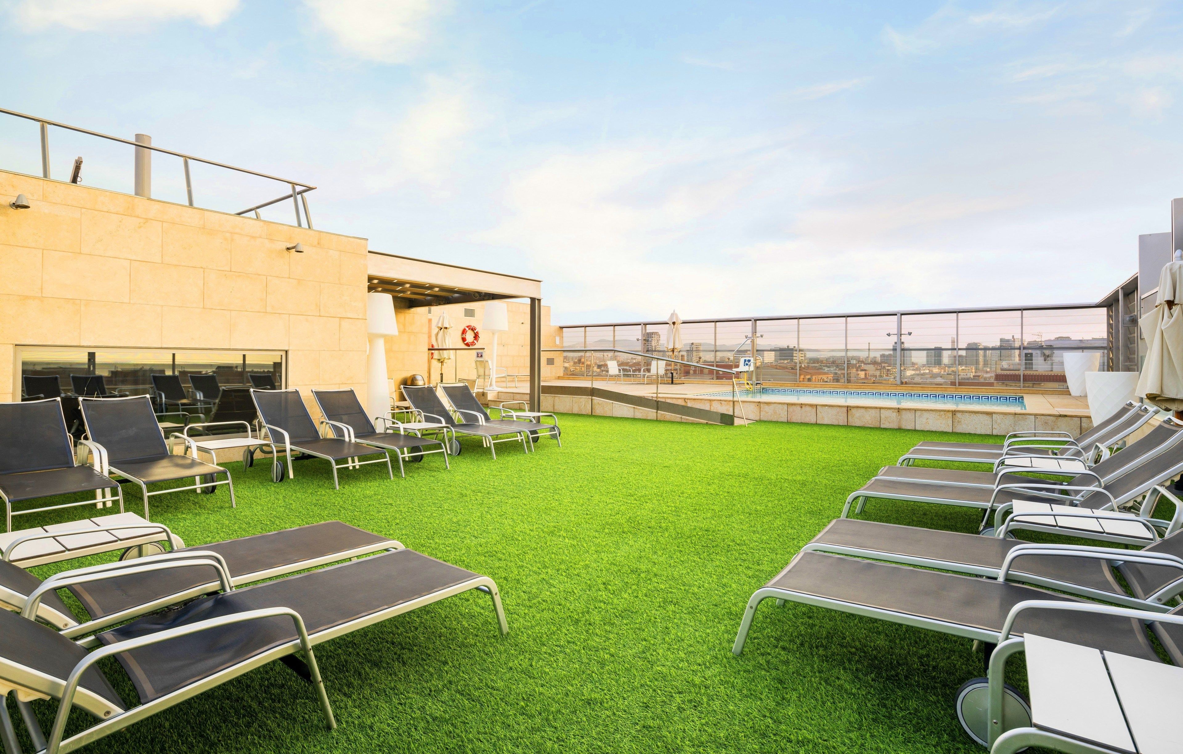Terraza en la azotea con tumbonas y piscina, con vistas despejadas al horizonte urbano.
