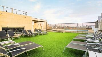 Terraza en la azotea con tumbonas y piscina, con vistas despejadas al horizonte urbano.