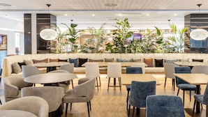 Un área de lounge moderna con un sofá semicircular, mesas redondas y sillas azules.