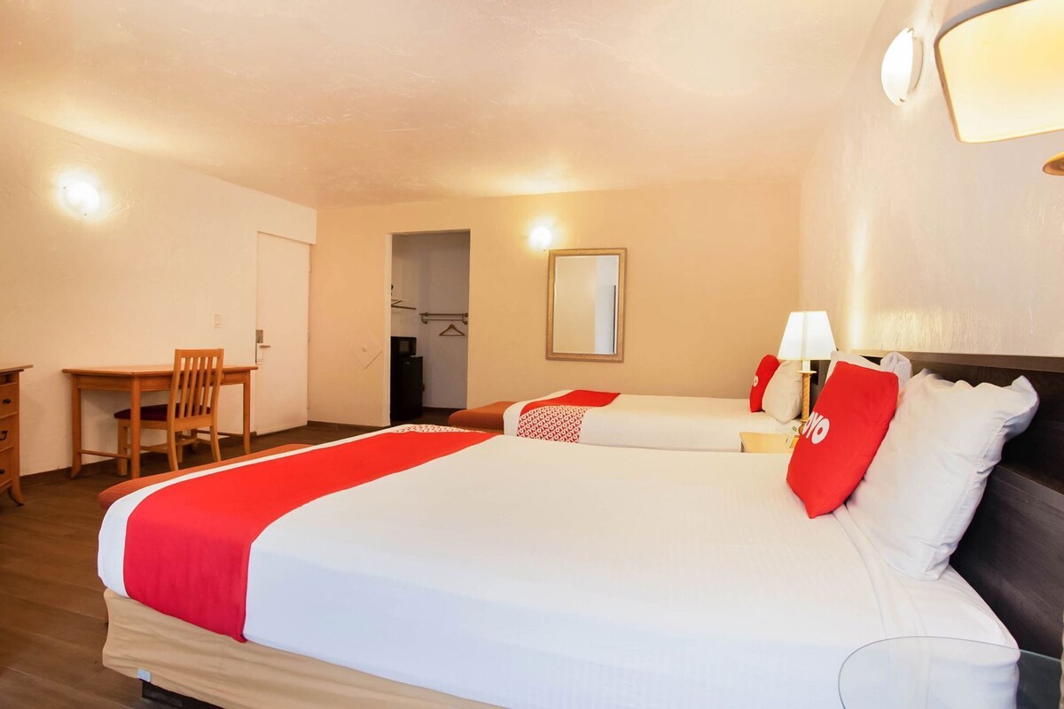 A hotel room with a large bed, a desk, and a chair.