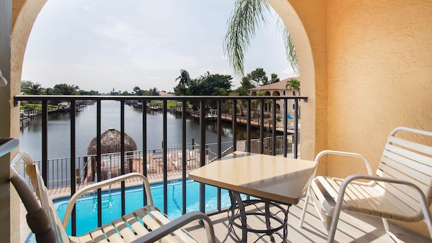 Un balcón con vista a la piscina, una mesa y sillas.