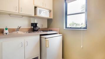 A compact kitchen with a microwave, coffee maker, and a small refrigerator.