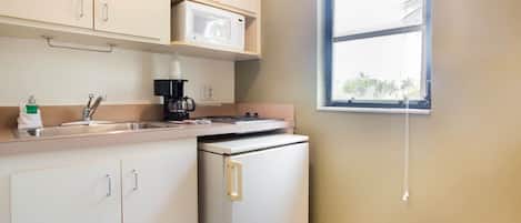 A compact kitchen with a microwave, coffee maker, and a small refrigerator.