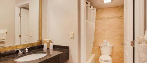 A bathroom with a marble sink, a white toilet, and a shower.