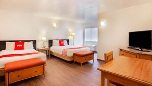 Una habitación de hotel con dos camas, televisión, escritorio y ventana con persianas.