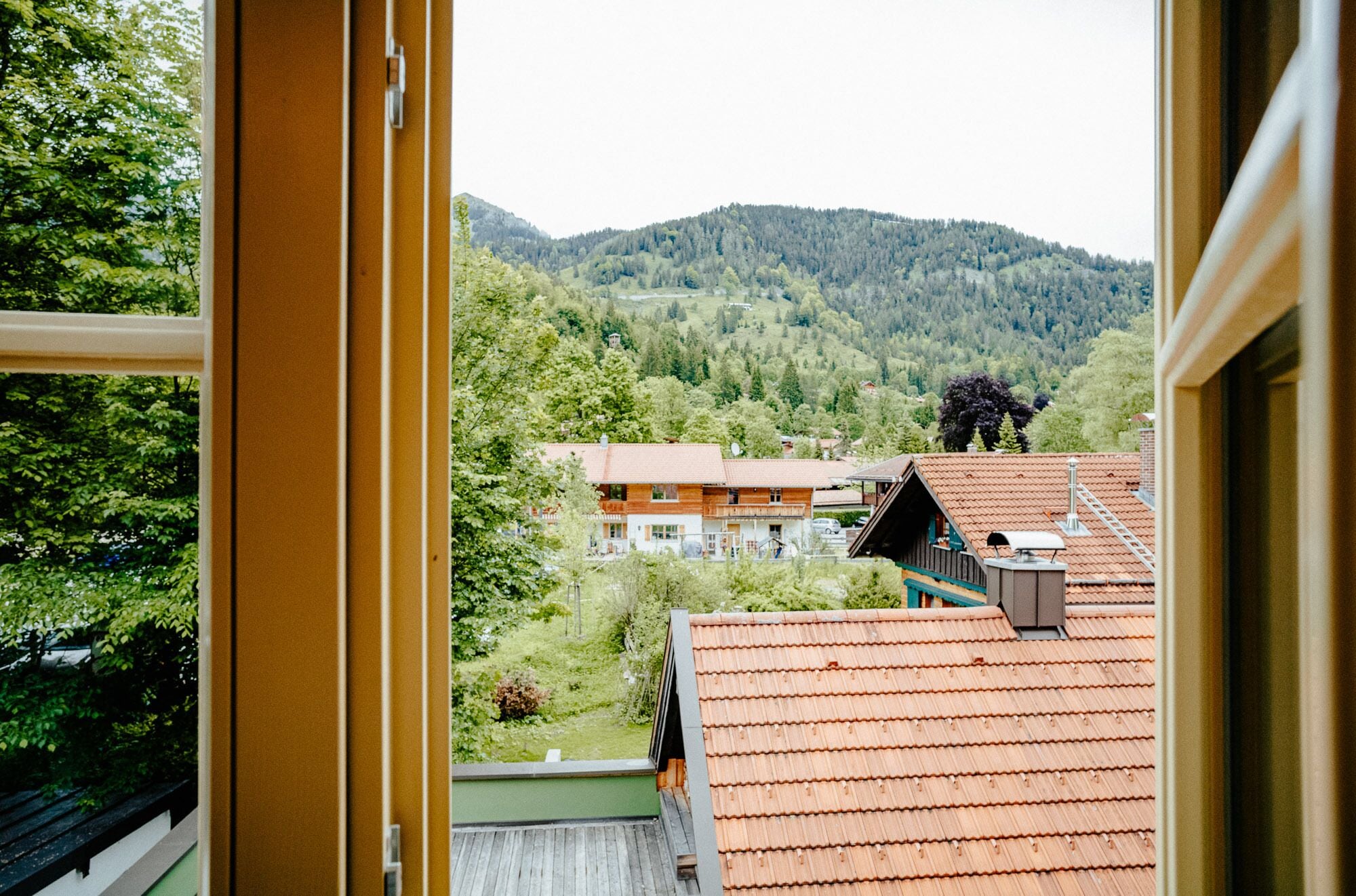 A view from a window overlooking a mountainous landscape with buildings.