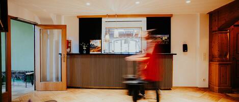 A modern interior with a wooden floor, a reception desk, and a large window.