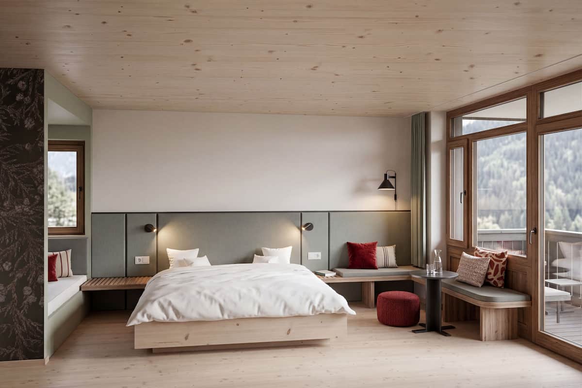 Ein Schlafzimmer mit Bett, einer Bank, einem Tisch und großen Fenstern.