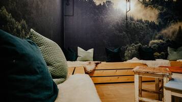 Una habitación acogedora con una pared oscura, un banco de madera y una pequeña mesa.