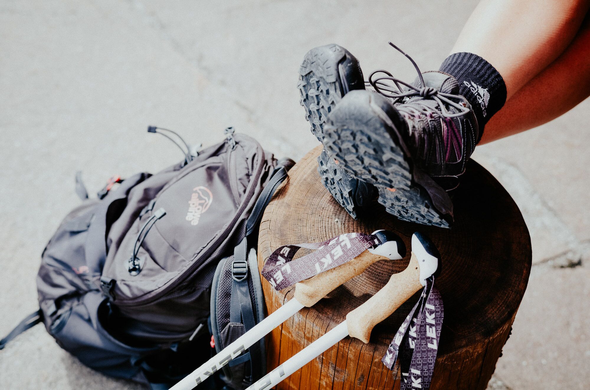Un tocón de madera con botas de senderismo, una mochila y bastones de trekking.