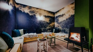 Een gezellige kamer met een open haard, een bank en een eettafel met fruit.