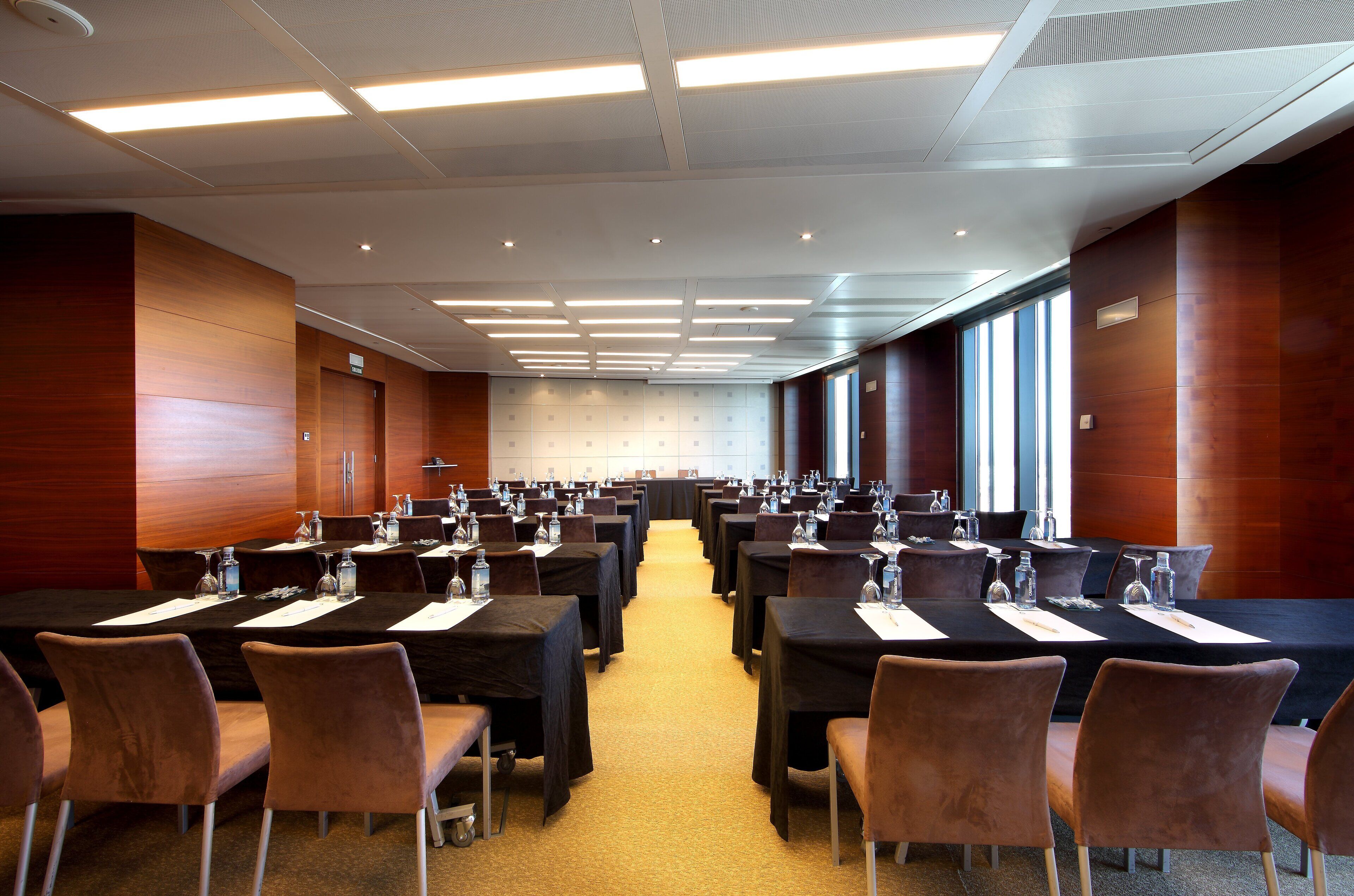 A conference room with multiple tables, chairs, and a carpeted floor.