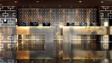 A modern reception area with a geometric patterned wall, a polished reflective floor, and a reception desk with a logo.