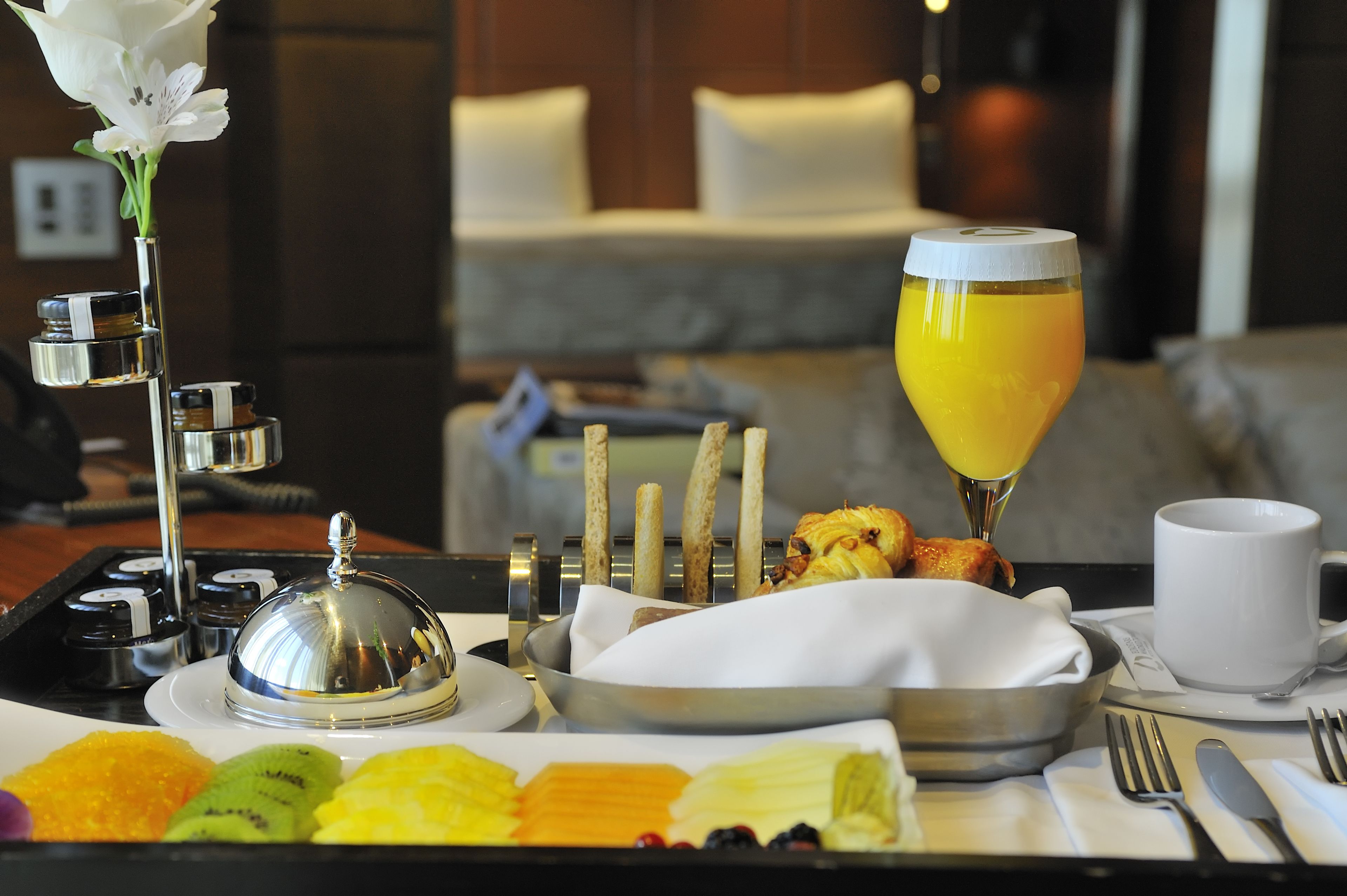 A breakfast buffet with a variety of fruits, pastries, and a glass of orange juice.