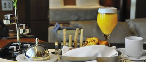 A breakfast buffet with a variety of fruits, pastries, and a glass of orange juice.