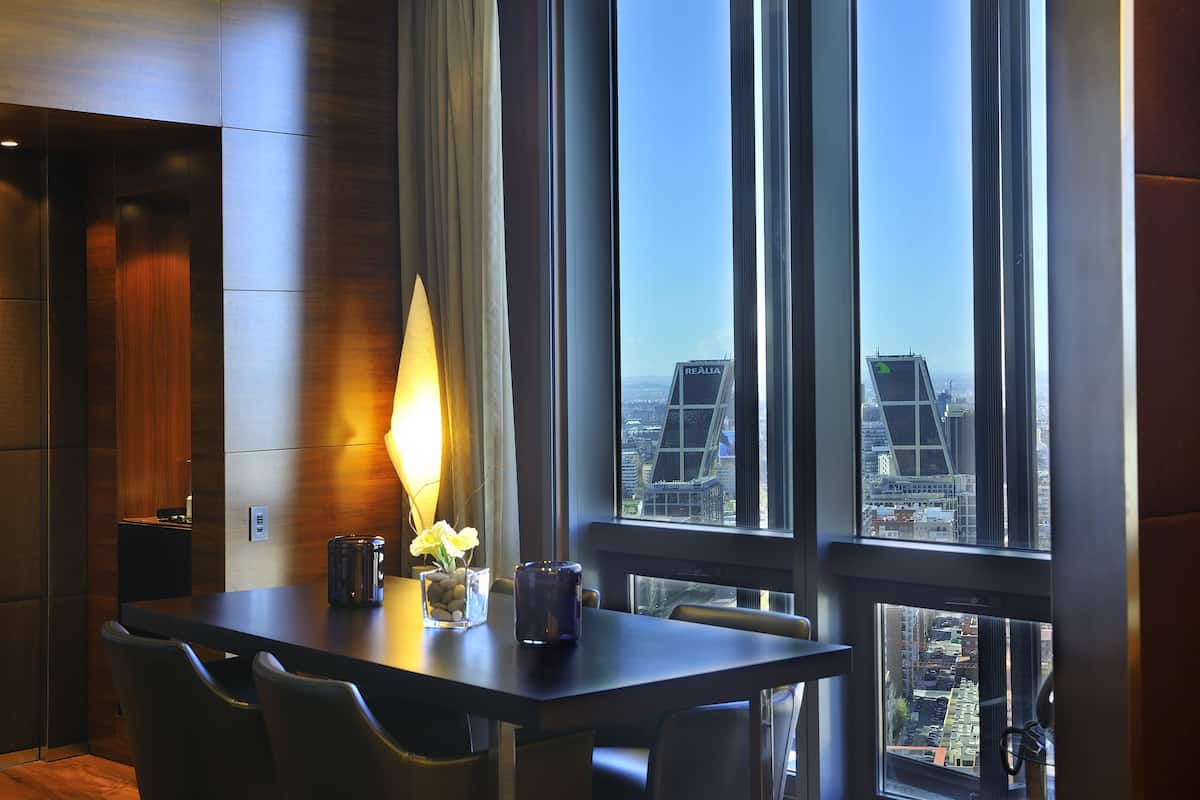 A modern dining area with a table, chairs, a candle, and a vase of flowers.