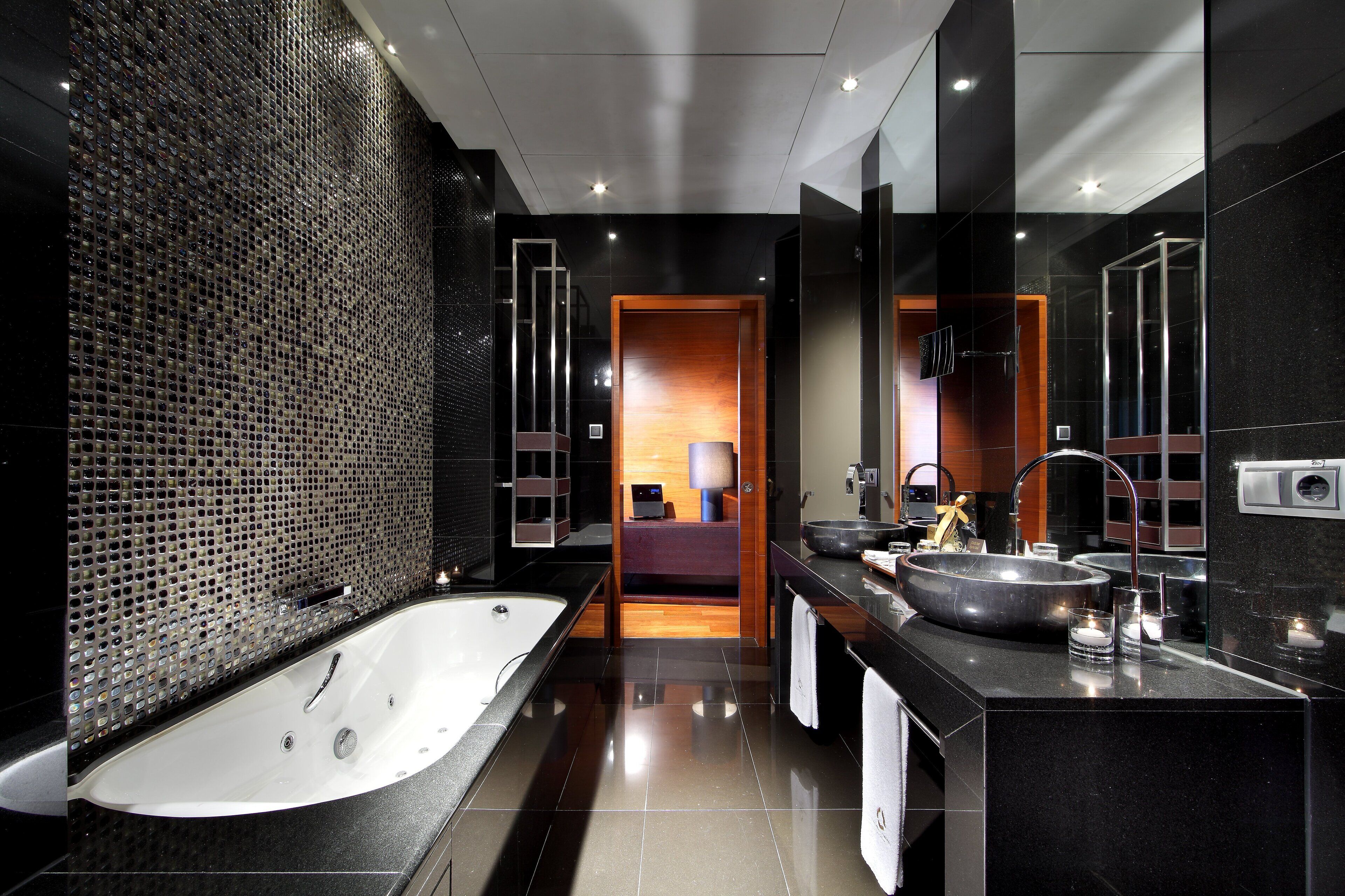 A modern bathroom with a large bathtub, a vanity with a sink, and a mirror.