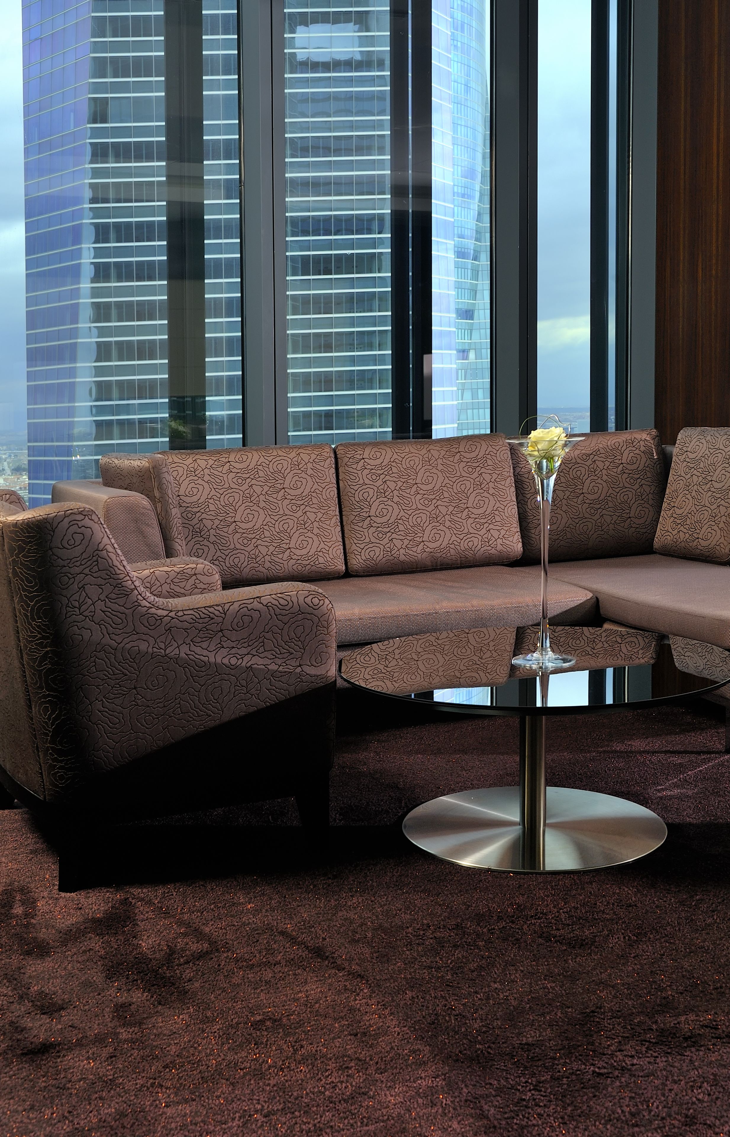 A modern living room with a sectional sofa, a round glass coffee table, and a decorative vase.