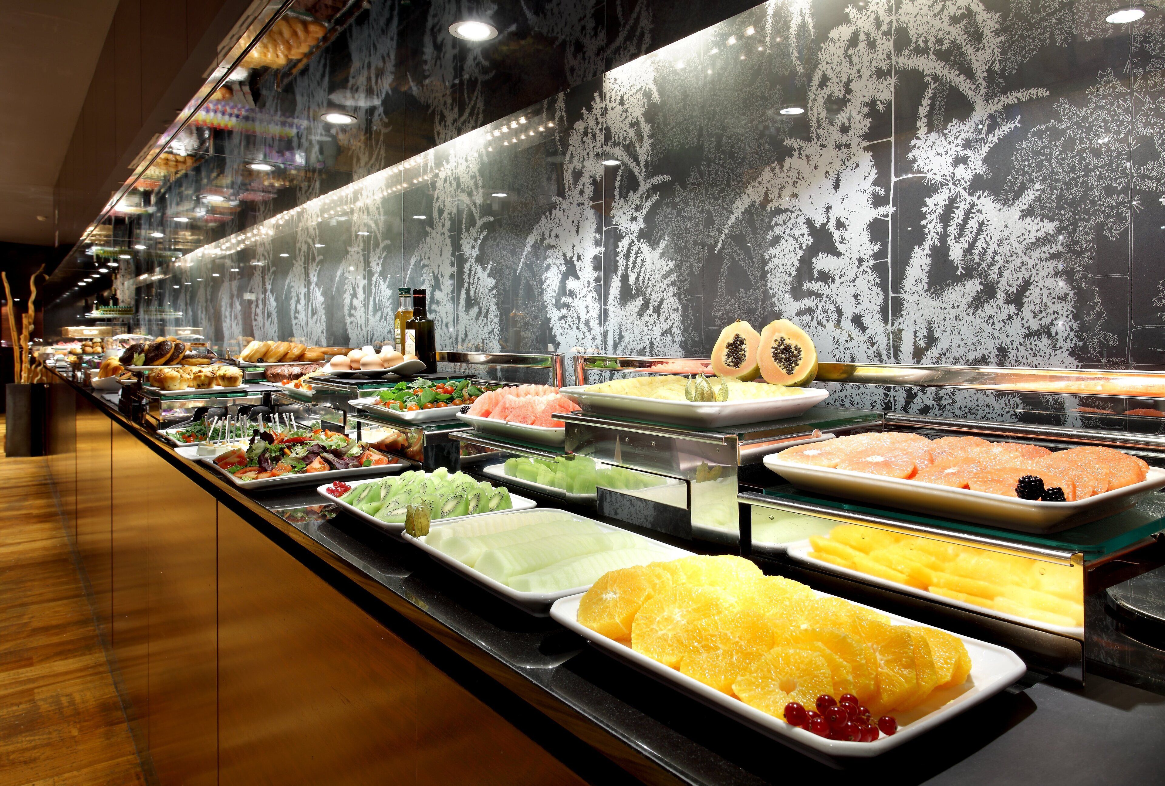 Buffet com diversas opções de comida, incluindo frutas, doces e frutos do mar.