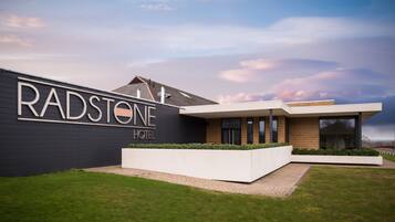 Un hotel moderno con un letrero grande que dice "RADSTONE HOTEL" y un diseño arquitectónico contemporáneo.