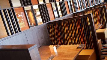 Un restaurante con mesas de madera y asientos tipo banqueta a rayas.