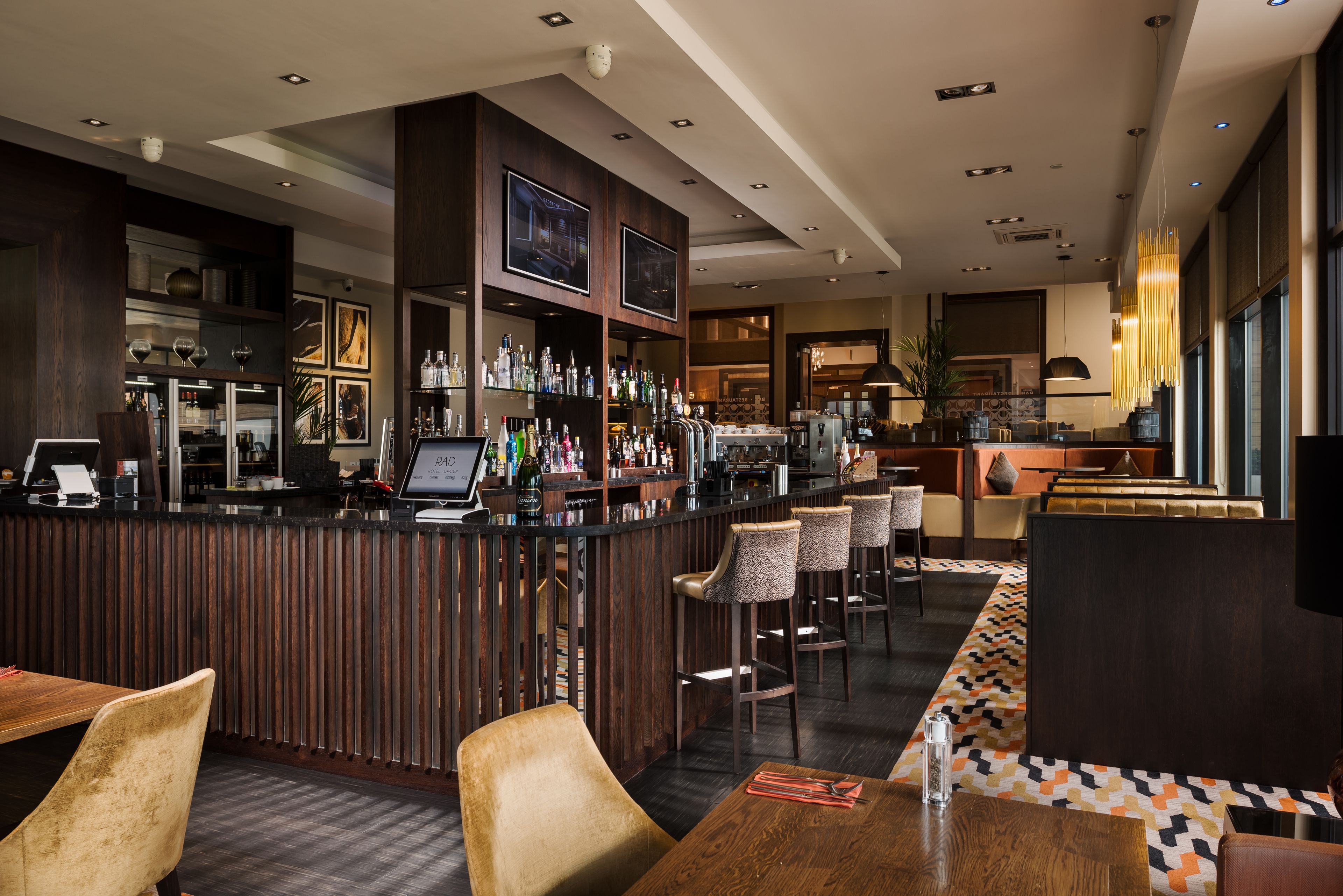 Un espacio de bar moderno con una barra de madera, taburetes y una variedad de botellas.