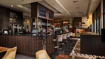Un espacio de bar moderno con una barra de madera, taburetes y una variedad de botellas.