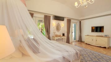 A bedroom with a canopy bed, a vanity with a mirror, a television, and a patterned rug.