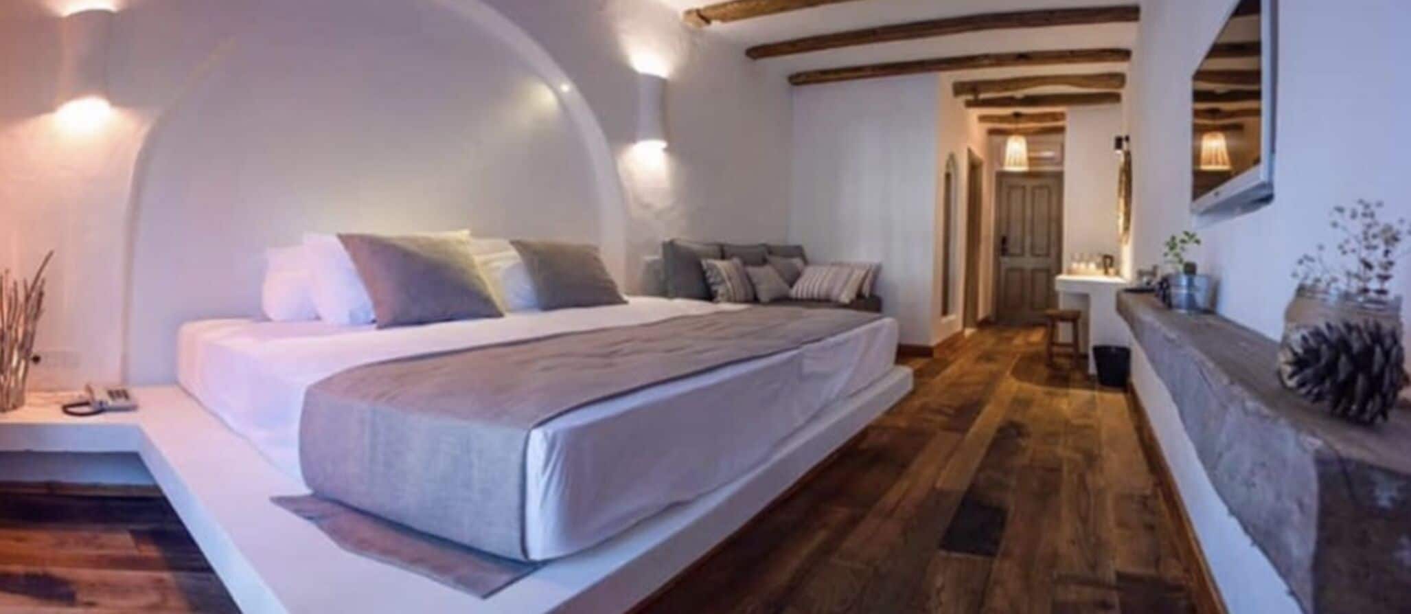 Un dormitorio moderno con una cama grande, suelo de madera y techo curvo.