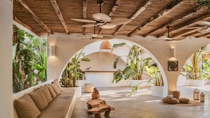 A spacious room with a high ceiling, a thatched roof, and a large arched window overlooking a lush garden. - Flamingo Hotel & Spa - Pet Friendly (Fethiye)