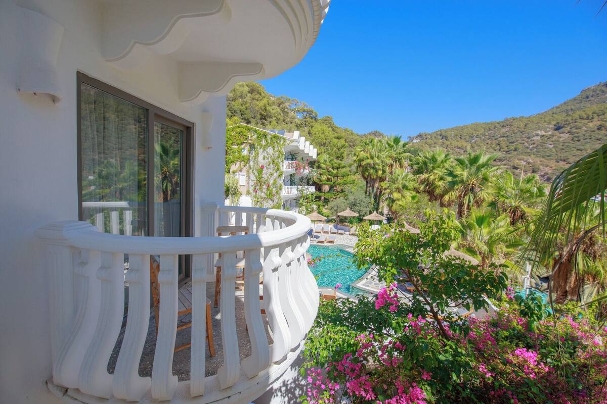 Un balcon avec une piscine, entouré d’une végétation luxuriante et offrant une vue sur un paysage montagneux.