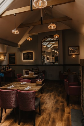 A restaurant with wooden tables and chairs, pendant lighting, and a high ceiling. - Atholl Arms Hotel (Dunkeld)