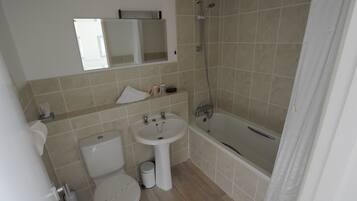 Een kleine badkamer met toilet, wastafel en douche.