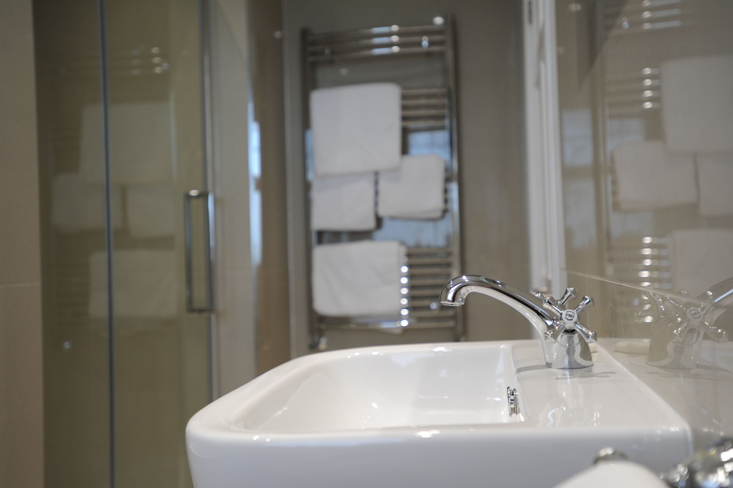 A bathroom with a white sink, chrome faucet, and glass shower enclosure.