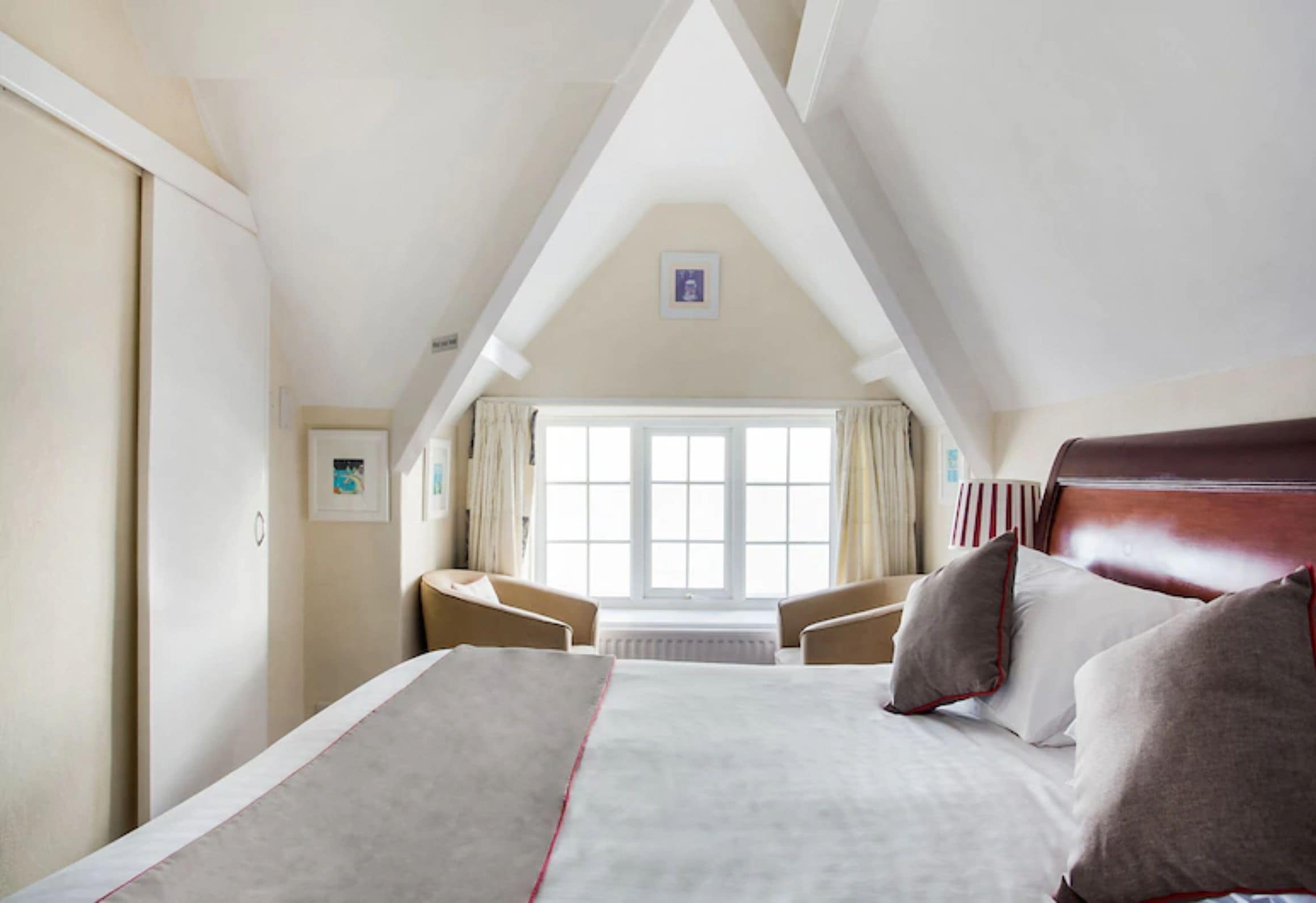 A bedroom with a large bed, a desk, and a window with curtains.