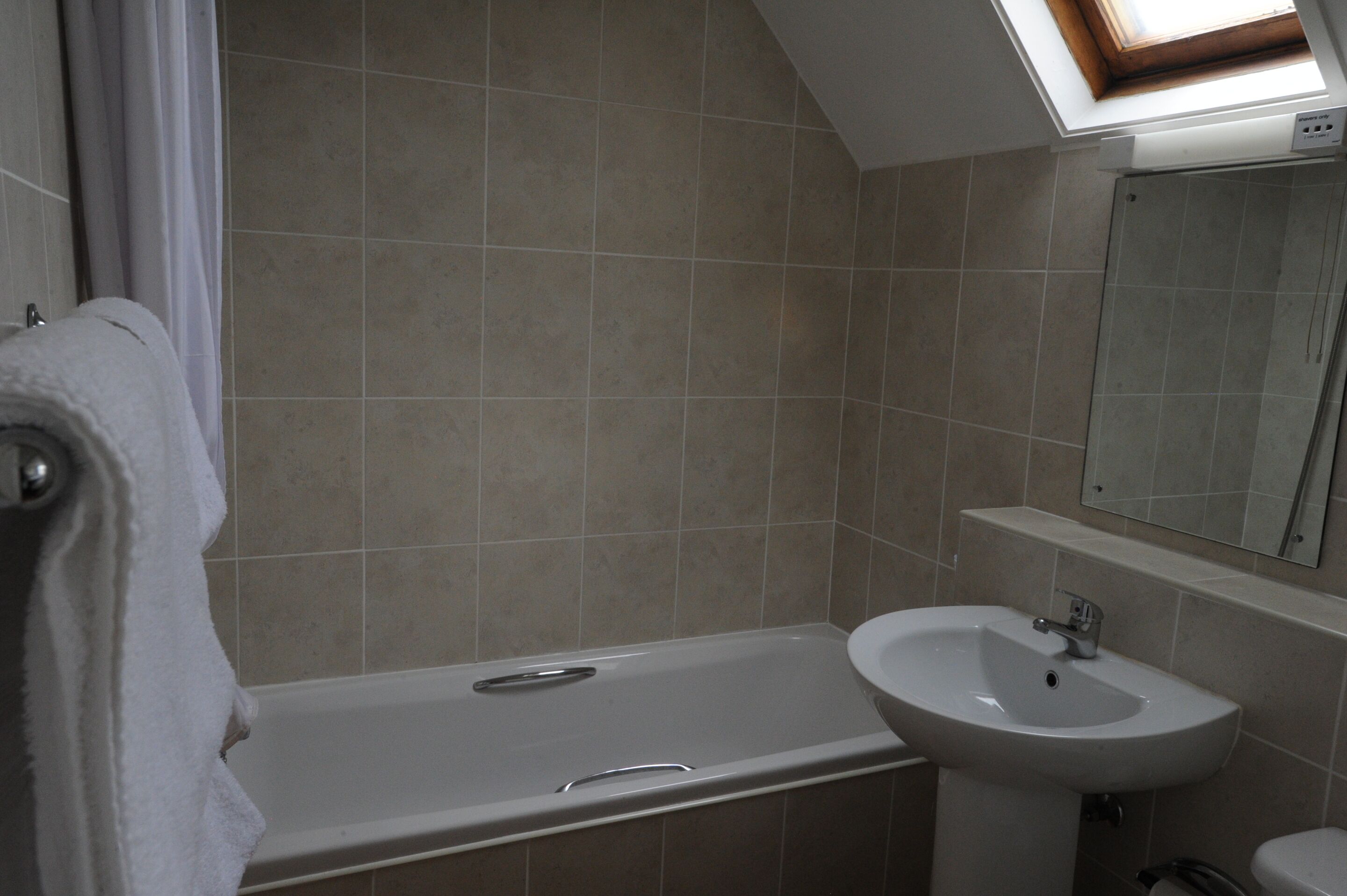 A bathroom with a bathtub, a sink, and a mirror.