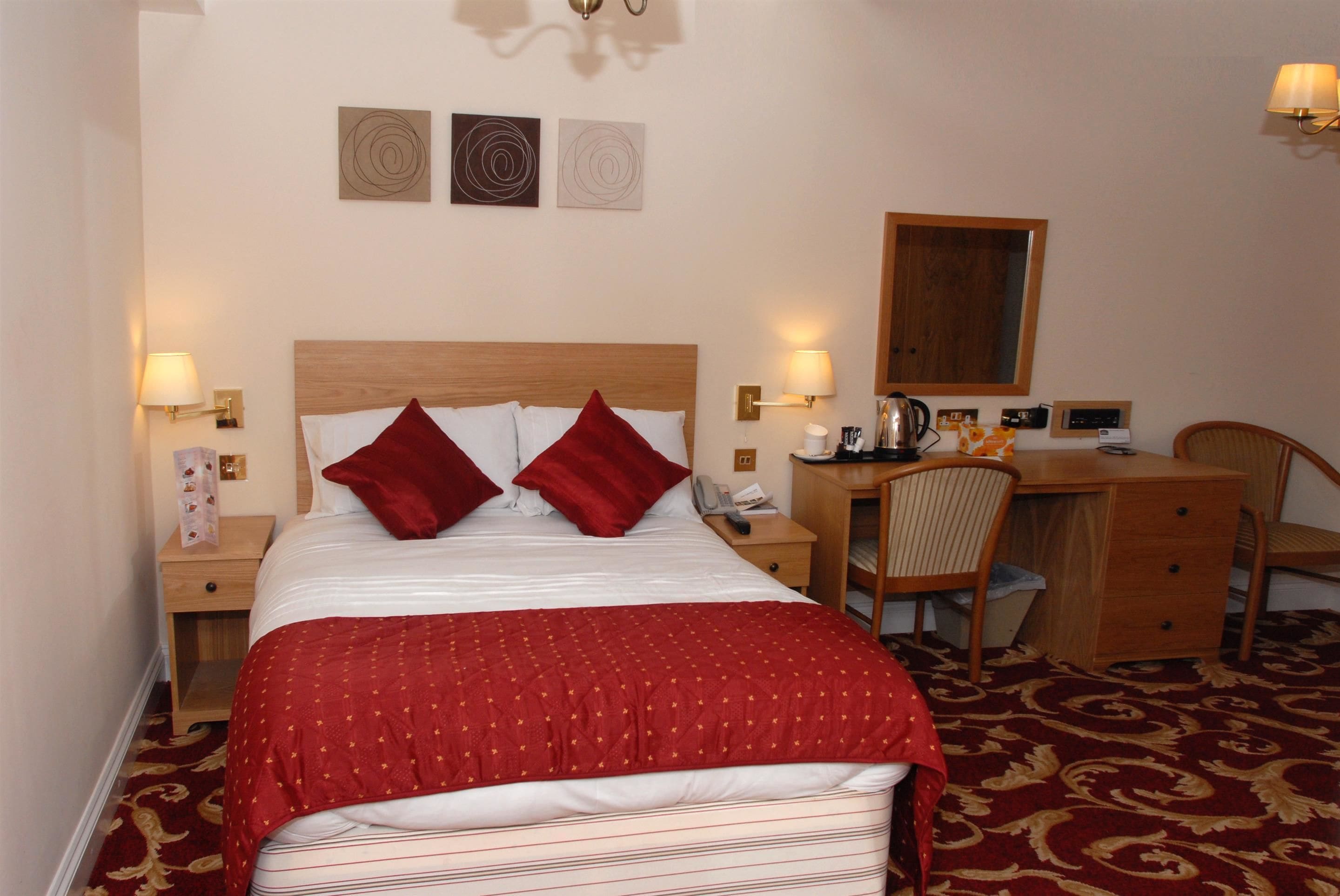 Ein Hotelzimmer mit Bett, Schreibtisch, Stuhl und Schreibtischlampe.