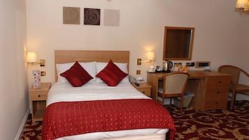 Ein Hotelzimmer mit Bett, Schreibtisch, Stuhl und Schreibtischlampe.