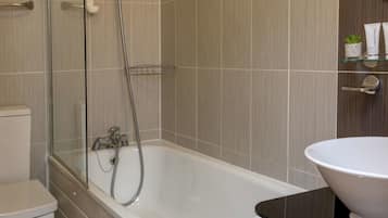 A modern bathroom with a glass-enclosed shower, a white bathtub, and a sink with a white basin.