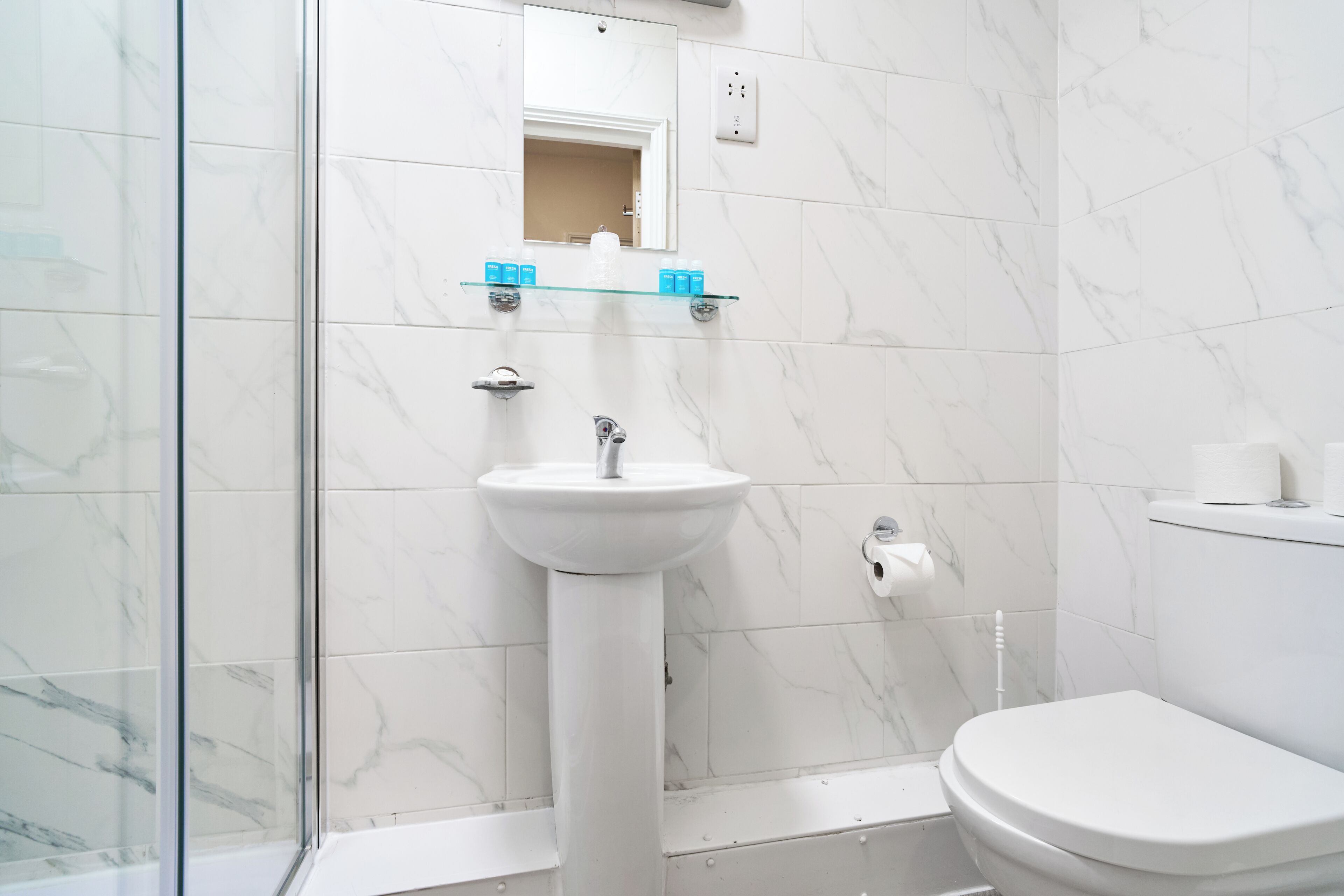 Ein Badezimmer mit einem weißen Waschbecken, einem Spiegel und einer Toilette.