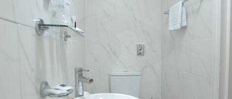 A bathroom with a white sink, mirror, and toilet.