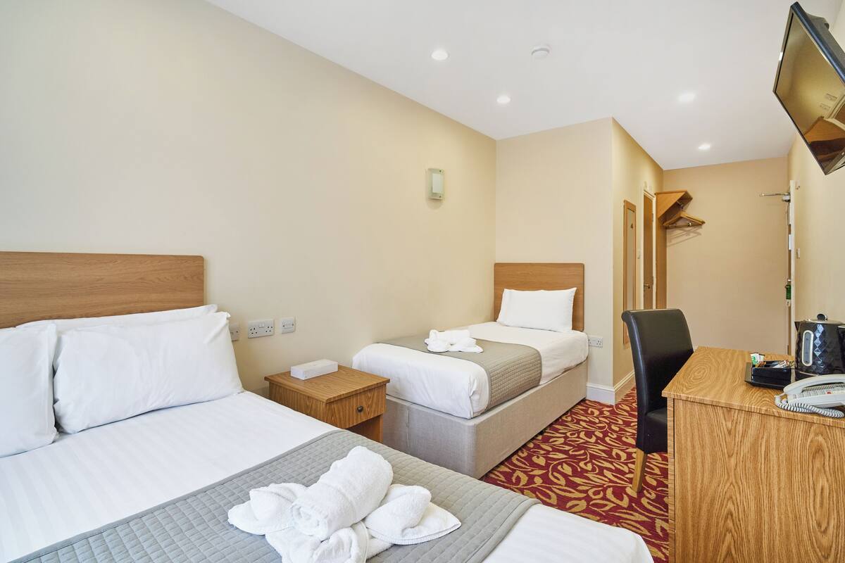 A hotel room with two beds, a desk, a chair, a television, and a telephone.