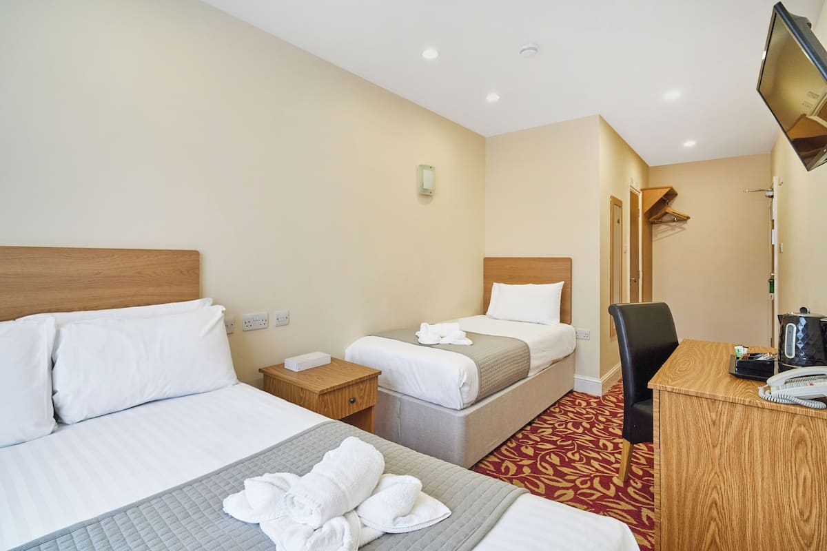 Ein Hotelzimmer mit zwei Betten, einem Schreibtisch, einem Sessel, einem Fernseher und einem Telefon.