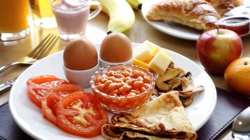 A breakfast plate with eggs, tomatoes, beans, cheese, mushrooms, and croissants.