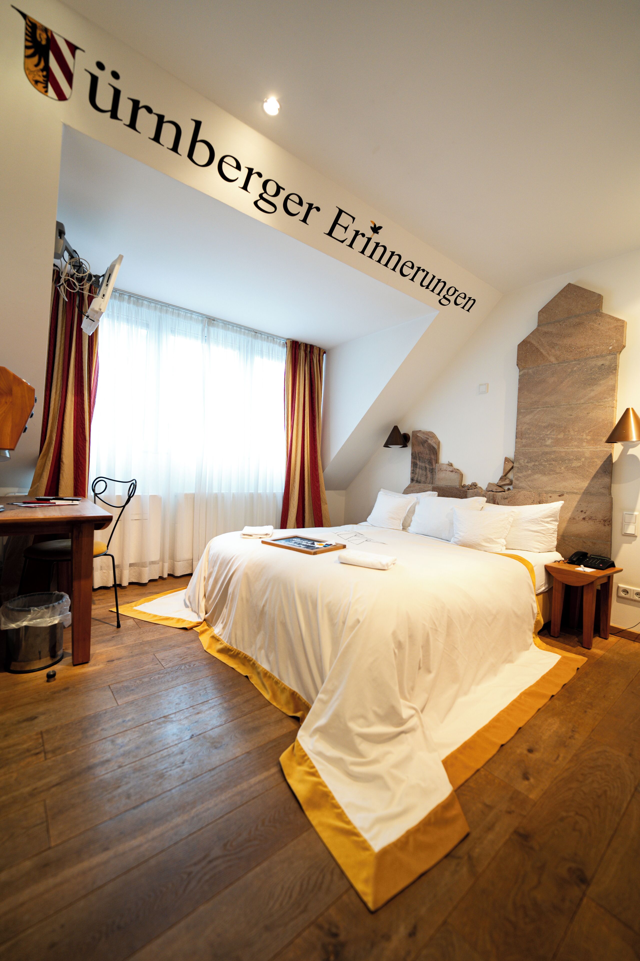Een hotelkamer met een groot bed, een bureau, een stoel en een wand van steen.