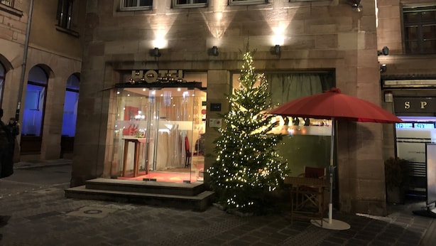 Entrada de hotel con un árbol de Navidad y un paraguas rojo.