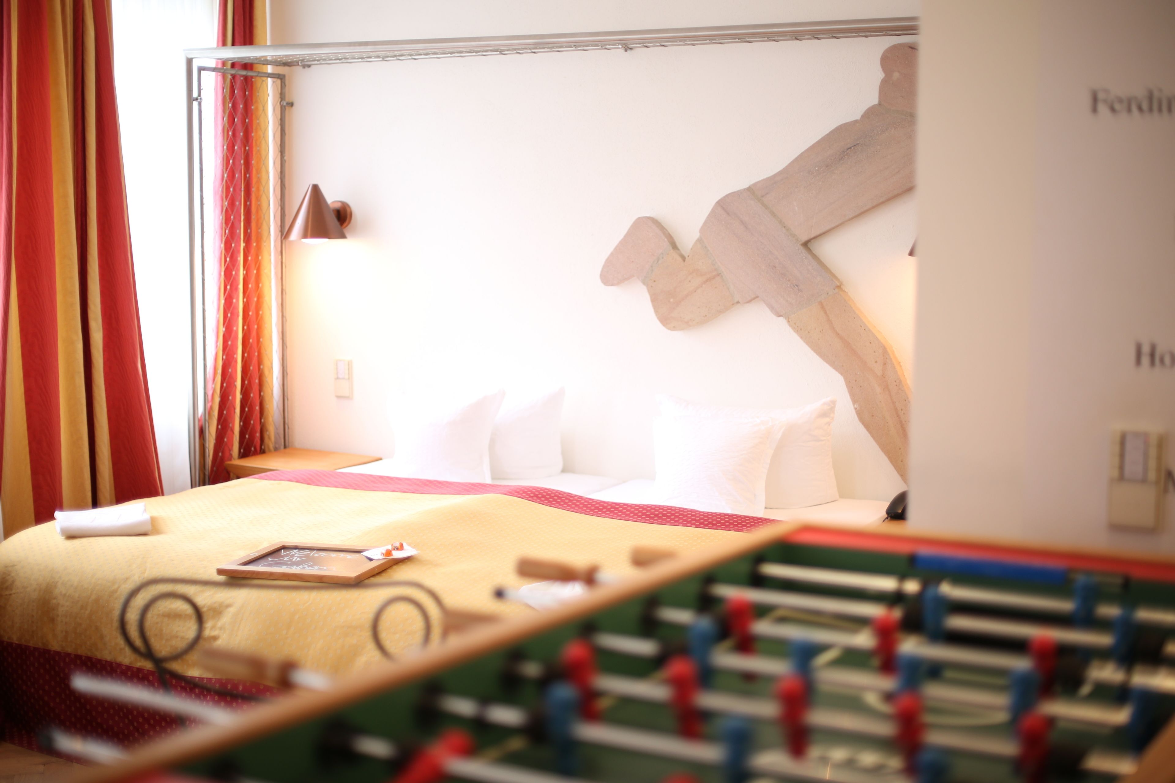 A hotel room with a bed, a foosball table, and a wall-mounted artwork.